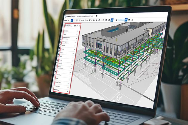 Hände auf einer Laptop-Tastatur. Der Bildschirm zeigt die Trimble-Connect-Software mit einem 3D-Gebäudemodell und einem Daten-Organizer-Fenster.
