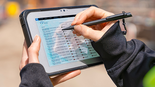Detailed view of a site inspector using a digital form on a rugged mobile device for construction quality control.