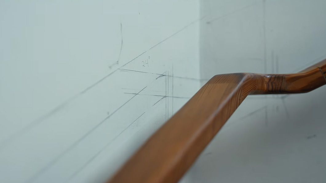 Image of a stair bannister, with pencil calculation drawings written on the white paint behind.