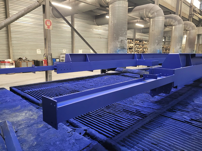 Close-up of a freshly painted blue steel structure on a powder coating line.