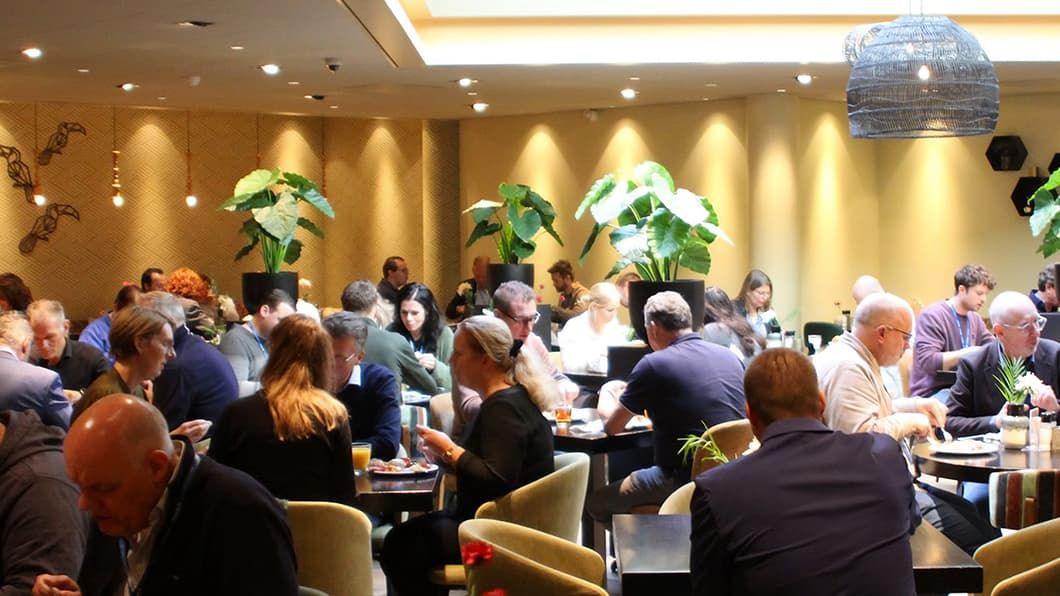 Deelnemers genieten van een lunch en een gesprek in een helder verlicht restaurant tijdens het ProjectSight-evenement.