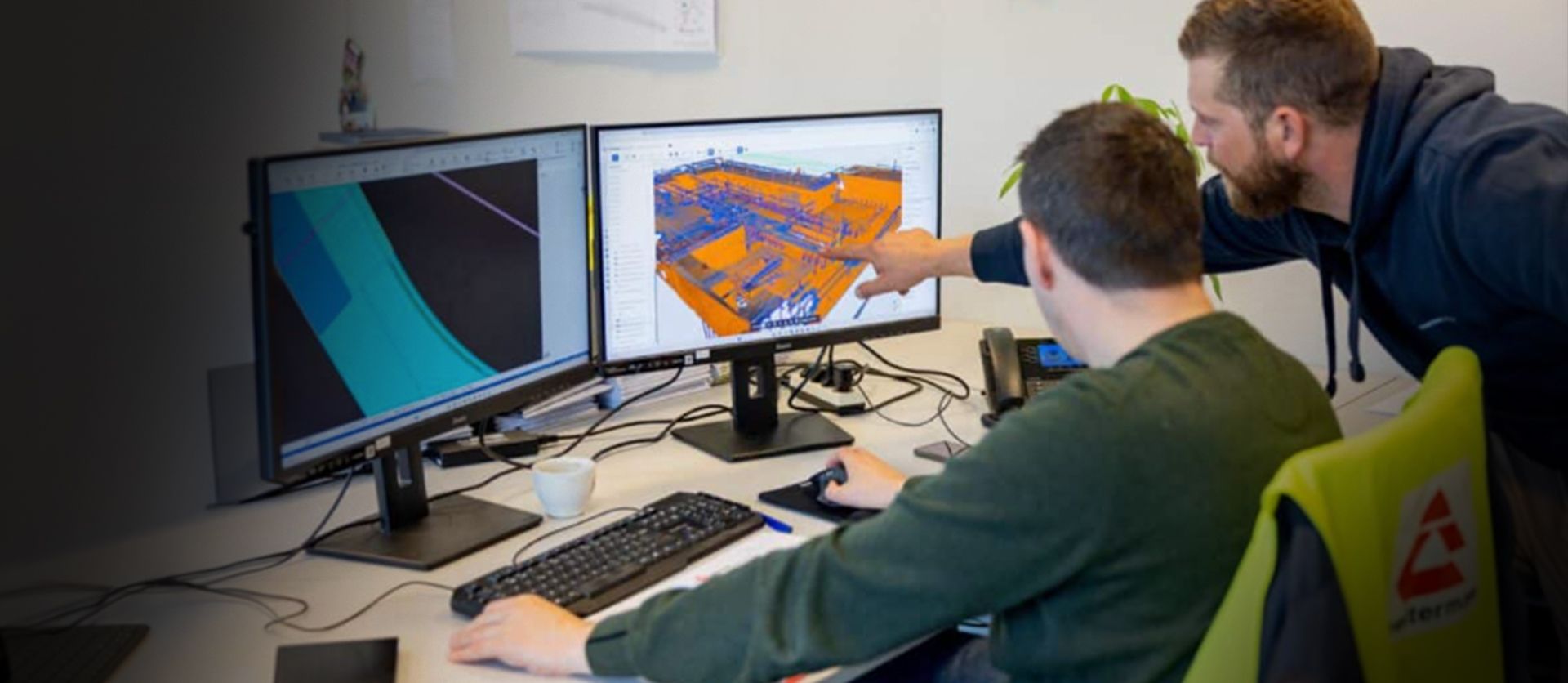Two men review the CAD file of a bridge being fabricated.