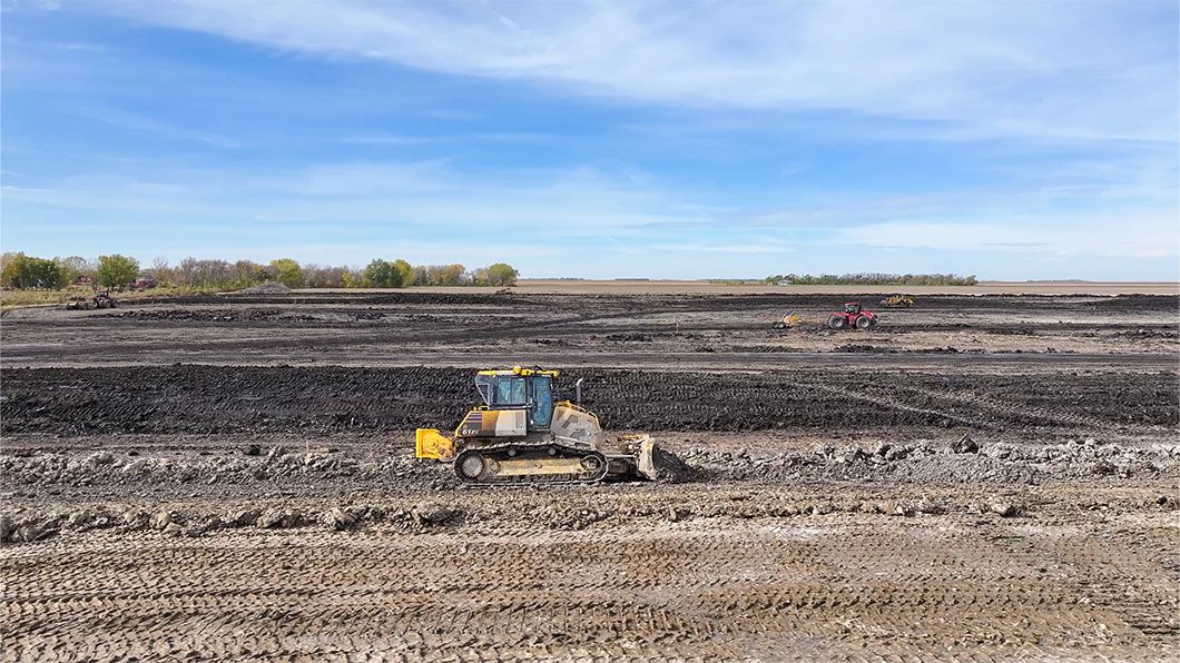A bulldozer with a scraper in a large agricultural field