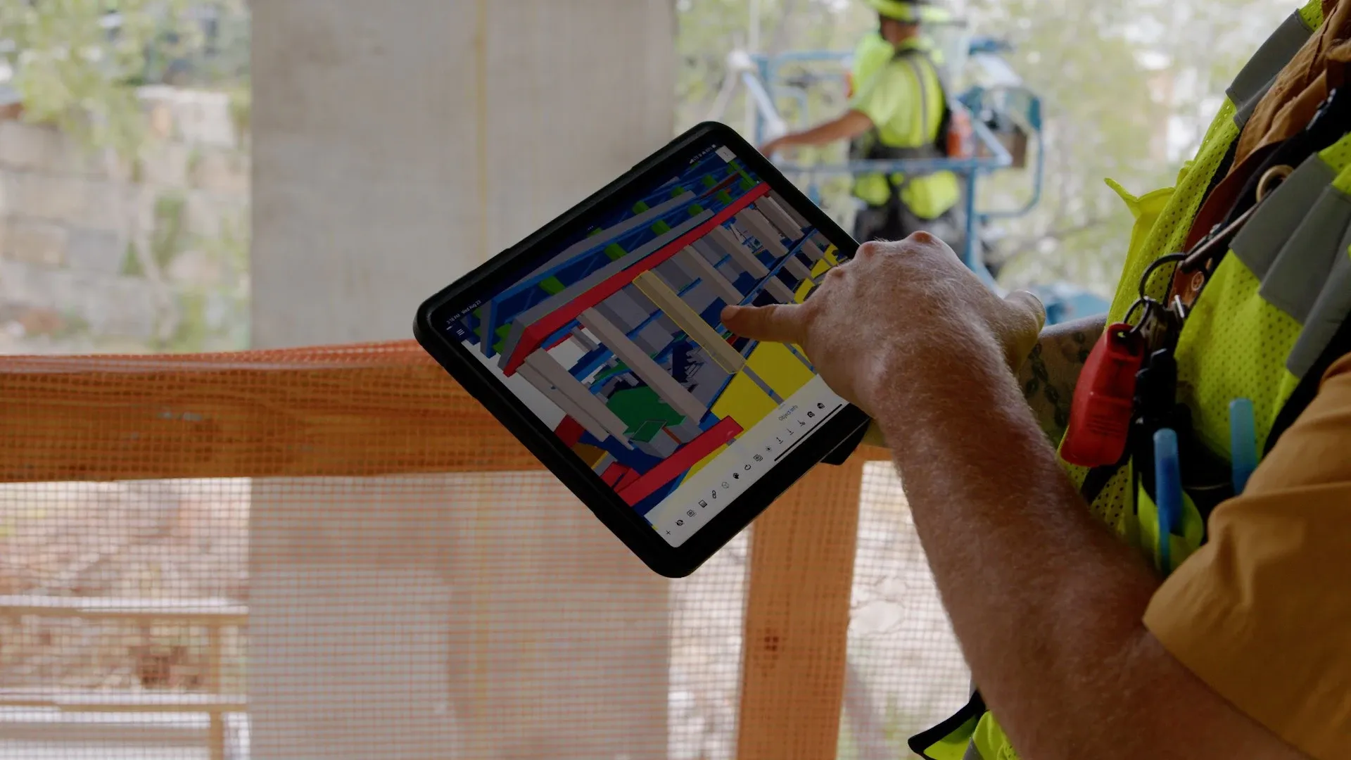 Construction worker using a tablet to view a 3D BIM model on-site for real-time coordination.