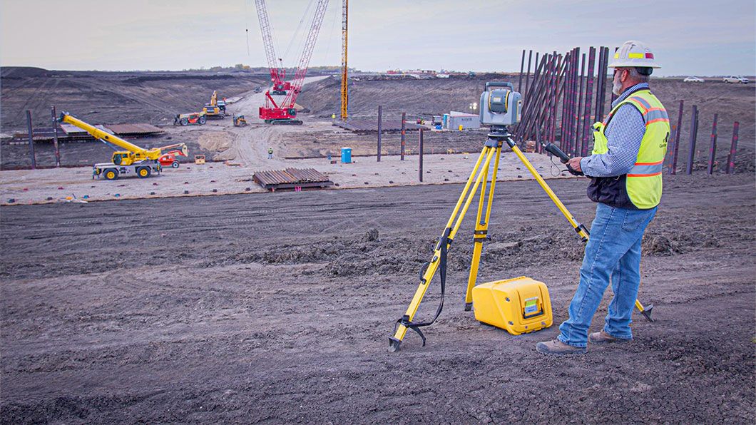 A man in safety gear on a construction site working with a Trimble total station