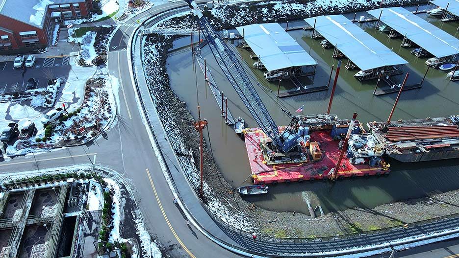 Crane on a barge in a marina with snow on the surrounding land.