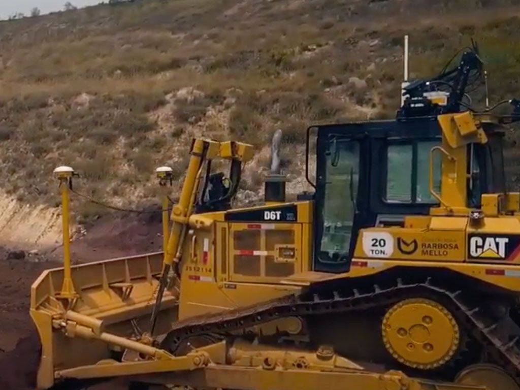 A yellow Caterpillar D6T dozer is working on a construction site, with a dirt embankment in the background.