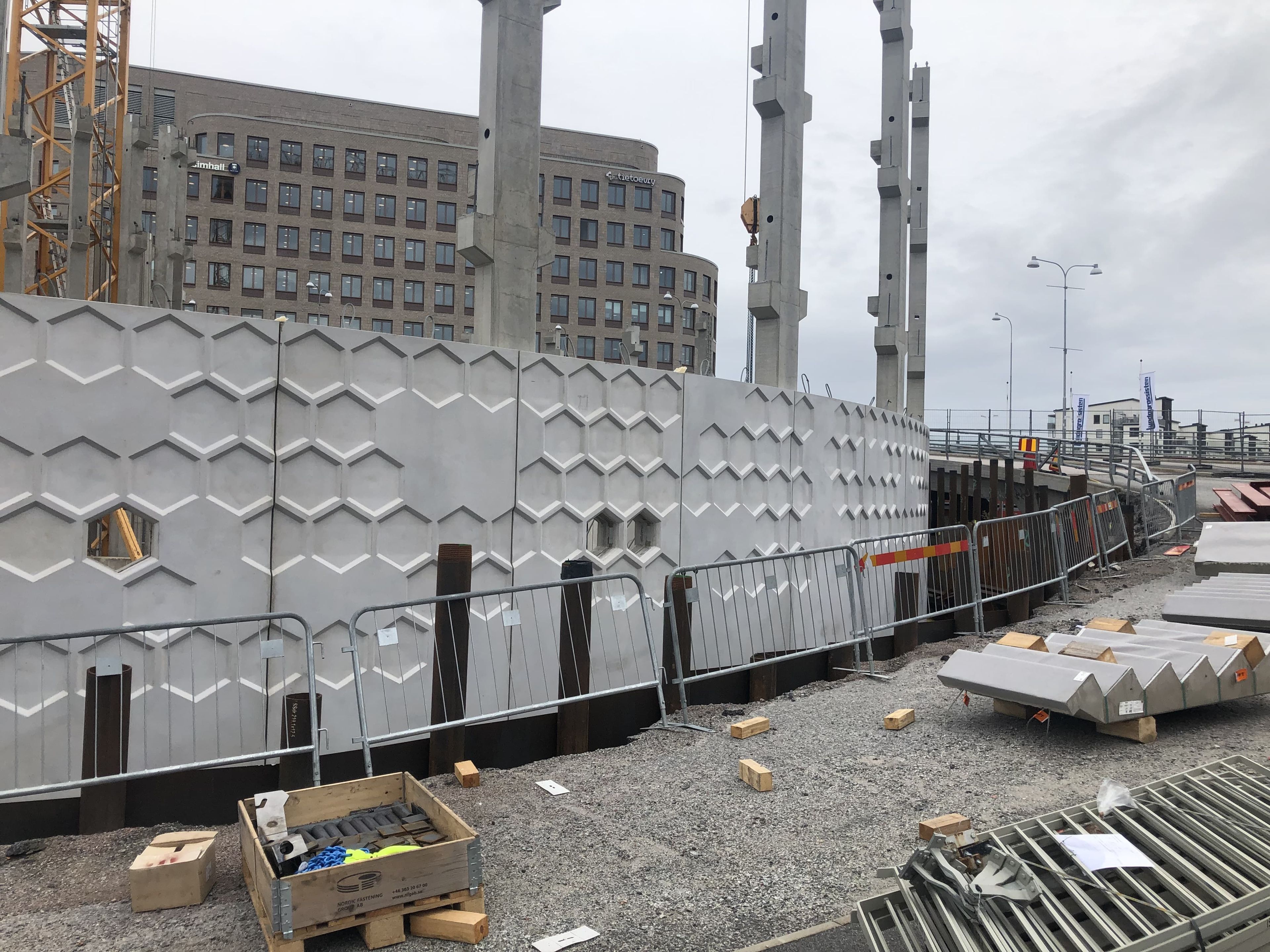 A concrete wall with a geometric honeycomb pattern is under construction.