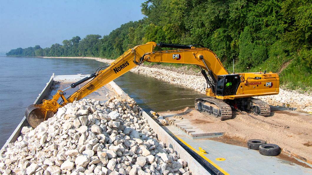 An excavator placing rock along the shoreline