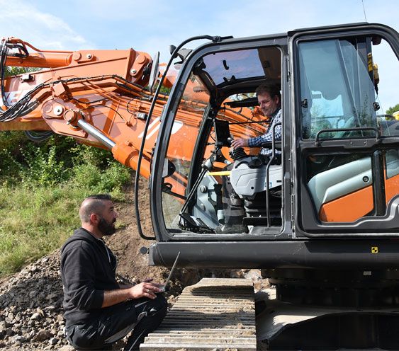 A worker setting up the system on the excavator