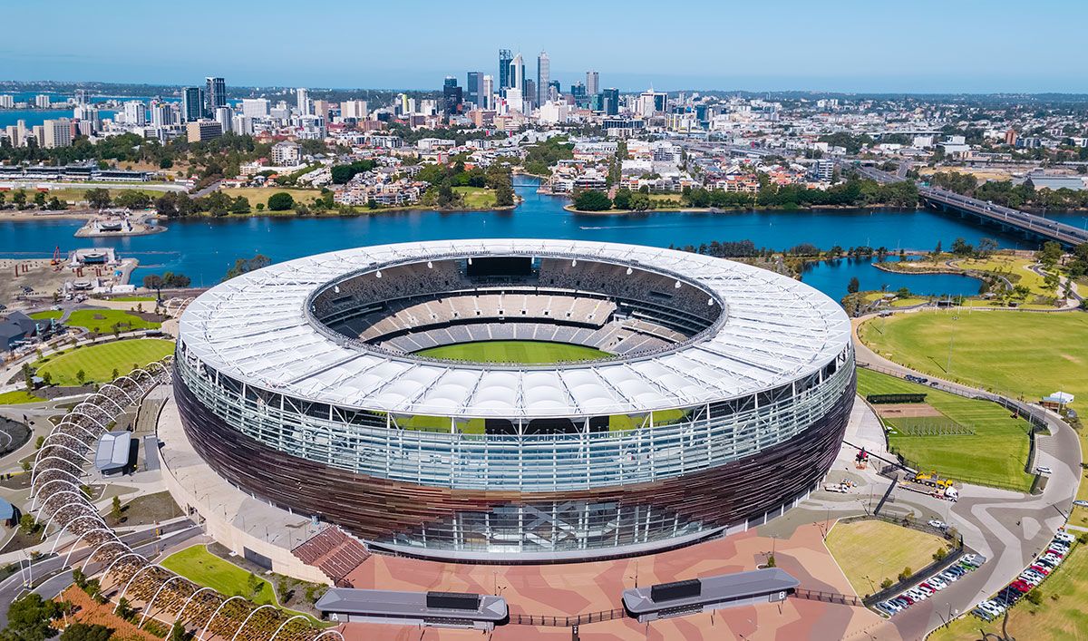 Aerial view of Optus Stadium in Perth, Australia, with the city skyline and Swan River in the background.