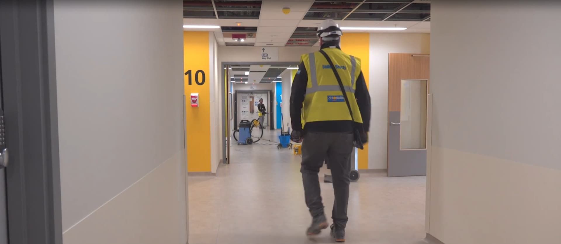Balfour Beatty worker in safety gear walking through a Midland Metropolitan Hospital hallway under construction.