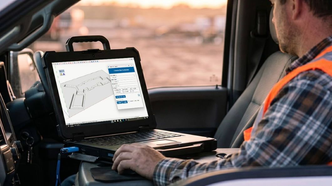 Construction worker using a rugged laptop in a vehicle cab to view a 3D site excavation model on SketchUp Pro Civil Contractor..