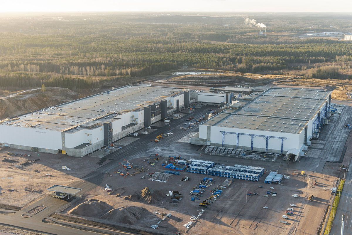 Aerial view of a large, modern industrial complex under construction, with multiple large buildings and surrounding undeveloped land.