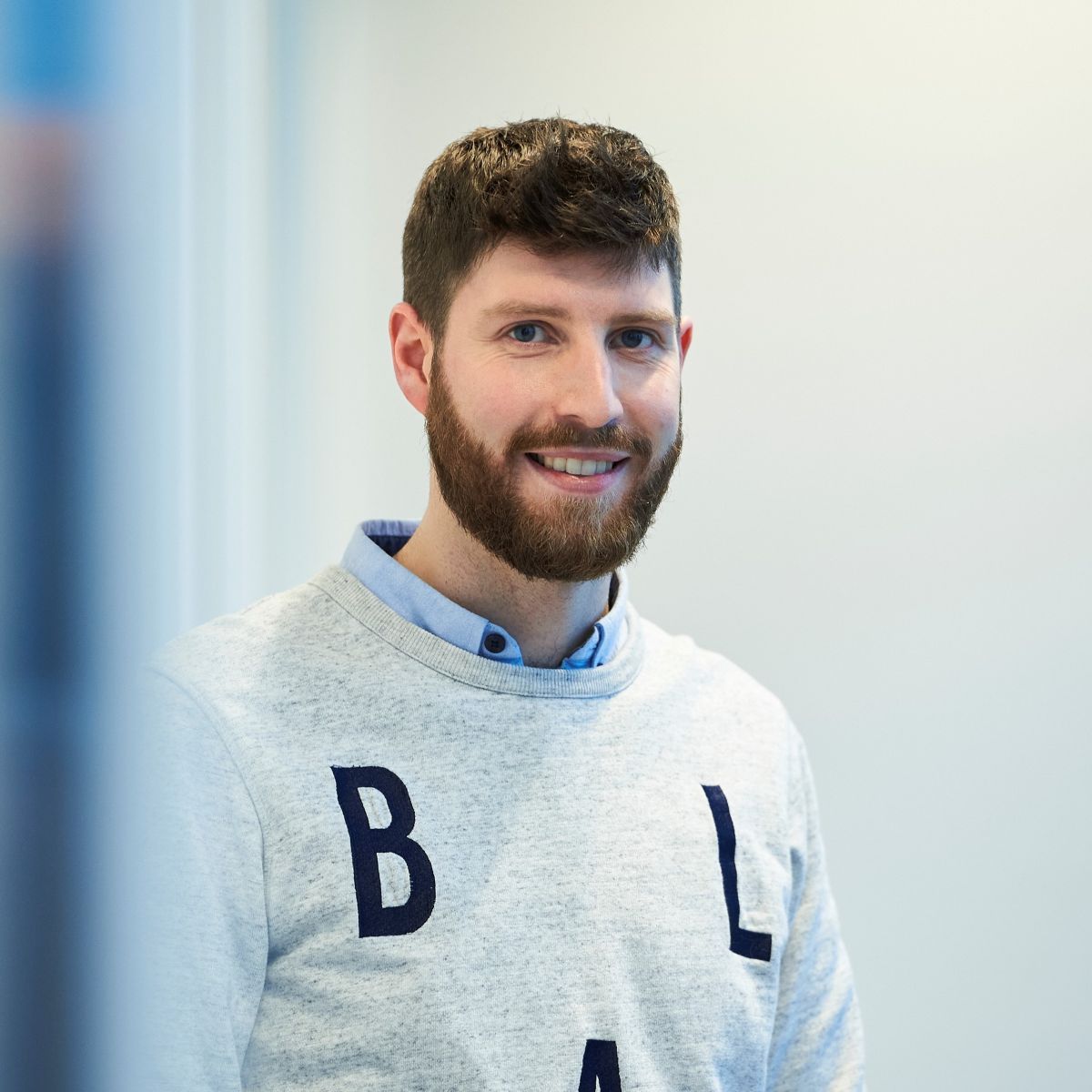 Robbe Verfaille smiles warmly, wearing a grey sweatshirt with blue letters across the chest.