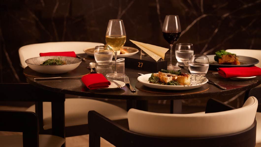 Detailed table setting in the JAL Lounge at Anfield, featuring red napkins, origami decor, and modern glassware.