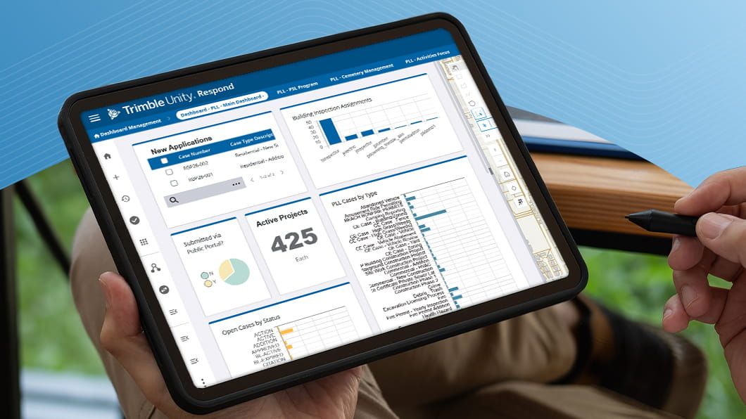 Person holding a tablet with a stylus, displaying the Trimble Unity Respond dashboard showing permit applications, project metrics, and charts.