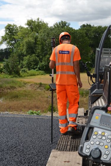 Worker checking height behind paver