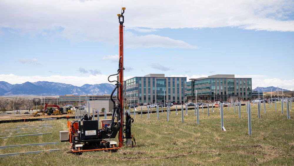 Pile driver installing piles for solar farm