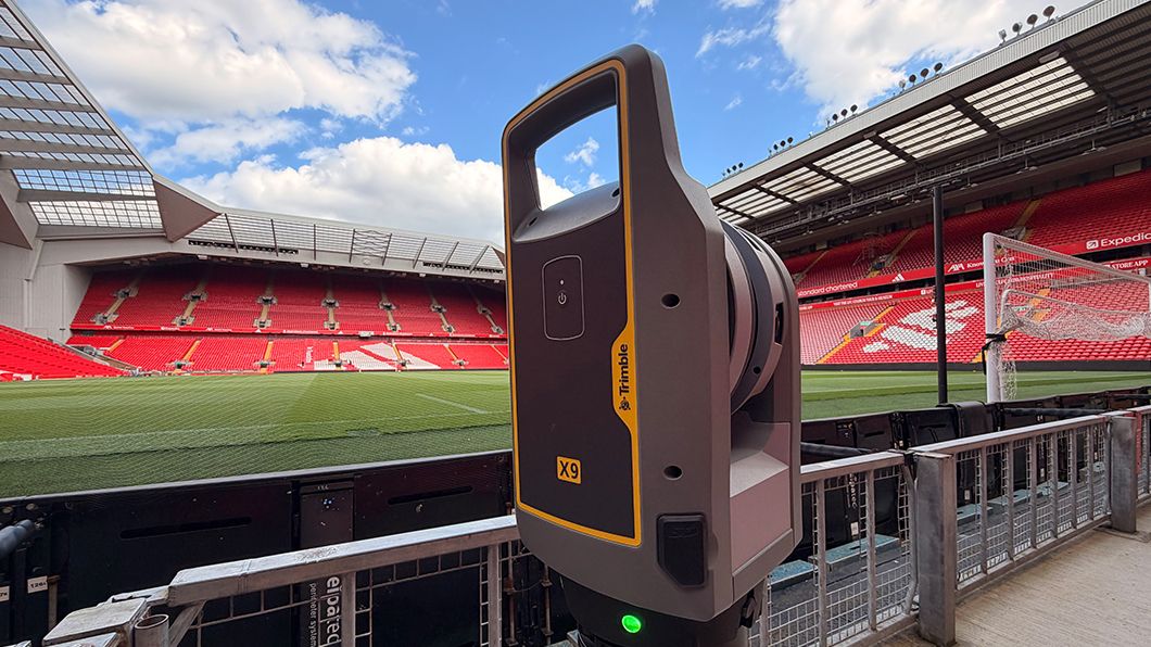 A Trimble X9 3D laser scanner, indicated active by a green light, surveys Anfield Stadium for AECO as-built documentation.