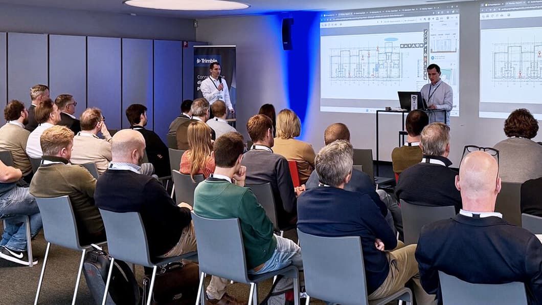 Een spreker presenteert een diagram over het verbinden van de digitale en fysieke wereld bij Trimble.