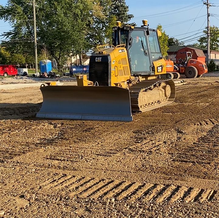 A yellow Caterpillar bulldozer sits on a dirt construction site, ready to grade the land.