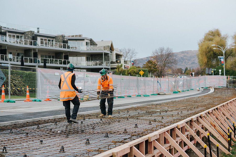 Construction workers carry rebar for concrete pouring at a job site.