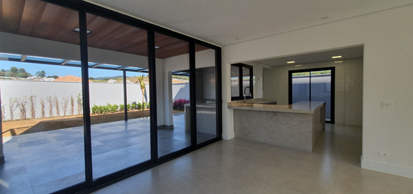 Modern open-plan living area with large glass sliding doors opening to an outdoor patio and a sleek kitchen island with a stone countertop.