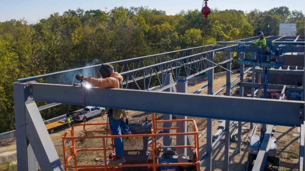 Person on a job site welding a steel structure.