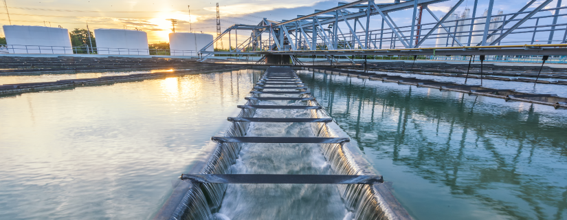 Water treatment plant with cascading water and industrial structures at sunset.