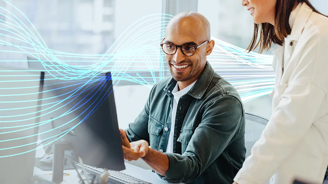 Two colleagues collaborating at a computer with digital wave graphics.