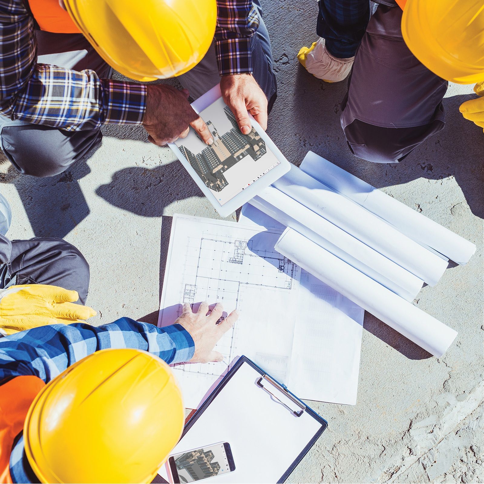 Construction workers collaborate on plans and a digital rendering of a building.