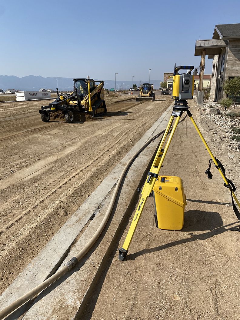 Construction site with heavy machinery and surveying equipment on a sunny day.