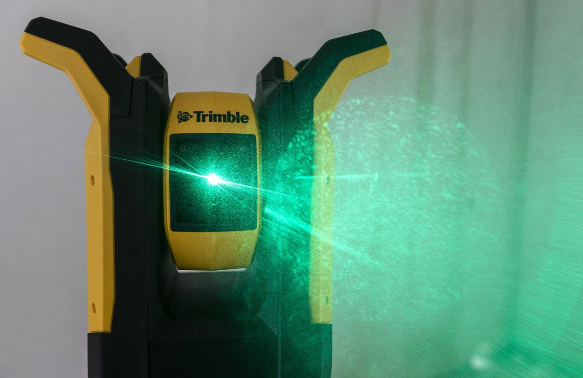 Trimble laser level projecting a bright green laser line across a wall.