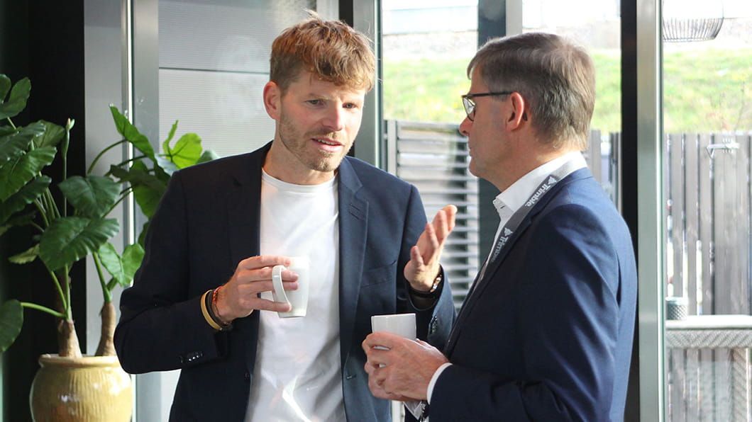 Twee mannen die tijdens de lancering van ProjectSight zaken bespreken onder het genot van een kopje koffie.