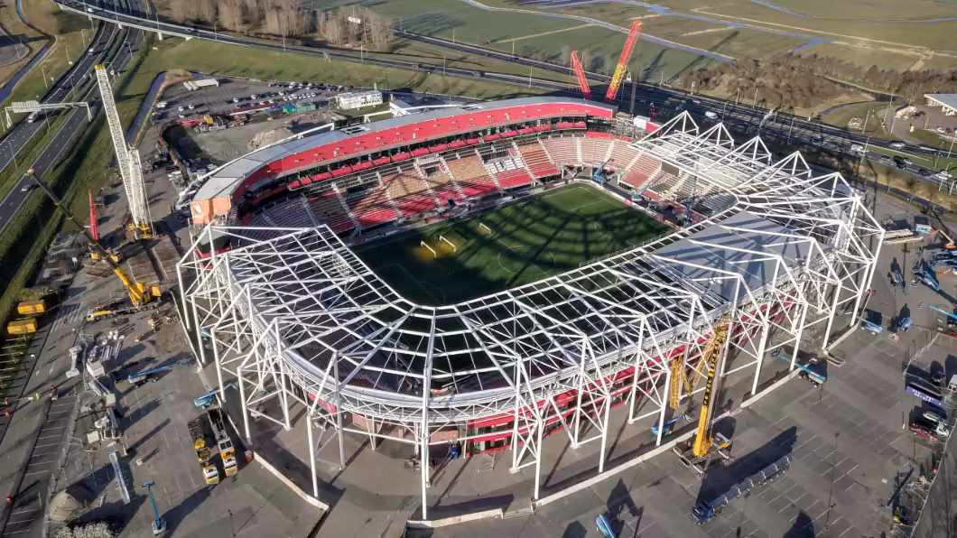 Aerial view of a football stadium under construction, with cranes and scaffolding surrounding the partially completed structure.