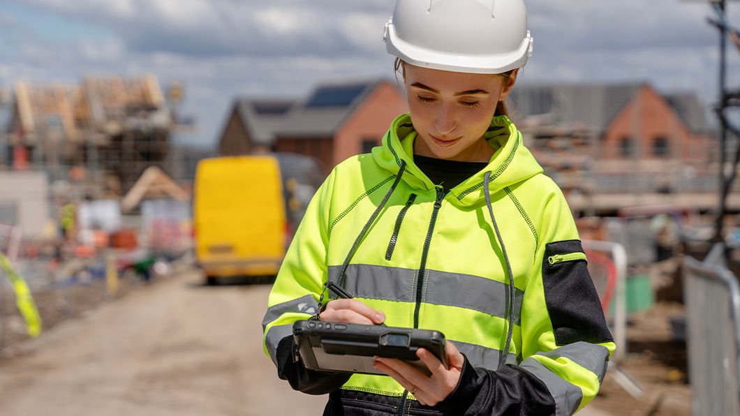 Construction worker utilising tablet to input construction data to central system.