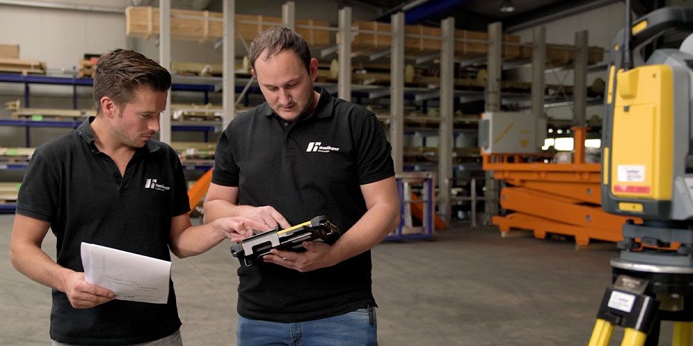 Zwei Mitarbeiter der Metallbau Haslinger messen mit der RTS673 Robotic Totalstation für eine Lagerbühne die Fußpunkte der Kon