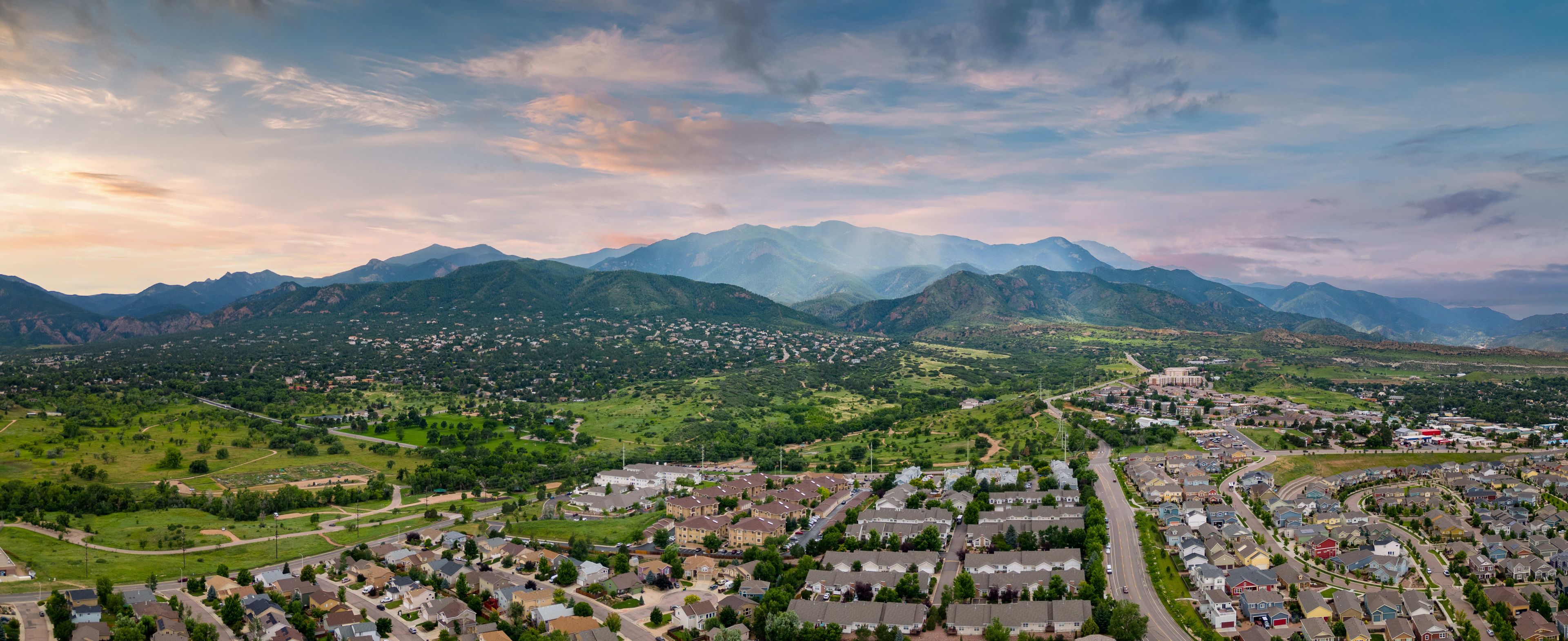Aerial view of El Paso County, Colorado, showcasing residential areas against a backdrop of green hills and mountains.