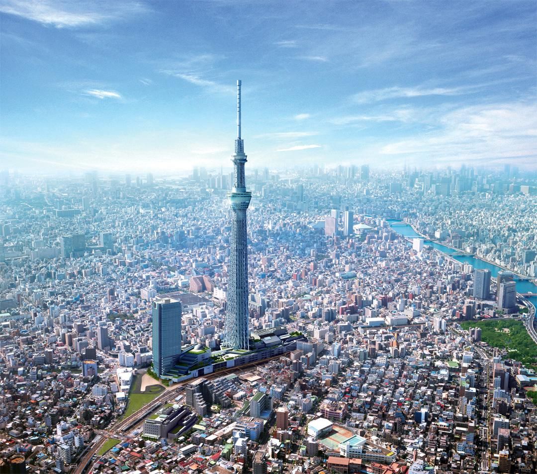 An aerial view of the Tokyo Skytree, a broadcasting and observation tower, towering over the dense cityscape of Tokyo, Japan.