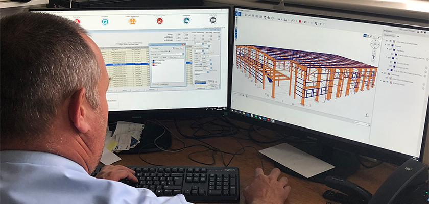 Waring Buildings employee sat at computer, Tekla PowerFab shown on two computer monitors