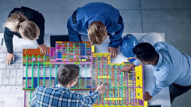 Top-down view of 4 professionals gathered around a table, collaborating on a colorful 3D Building Information Modeling (BIM)