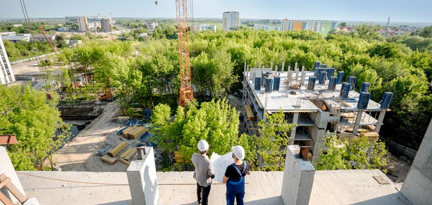 Two construction workers looking at a greener and more sustainable construction site surrounded by trees