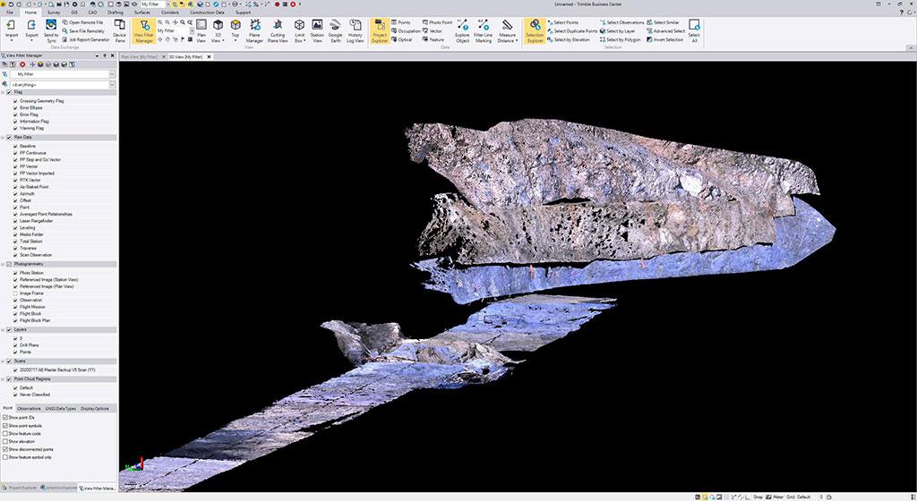 A software screenshot of Trimble Business Center showing a 3D point cloud model of a rocky, excavated terrain against a black background.