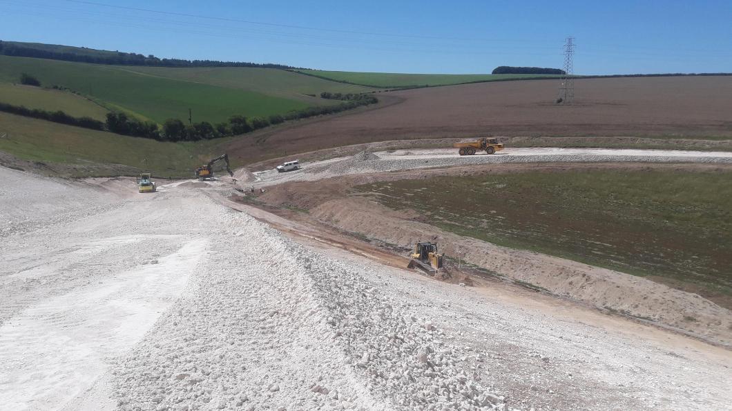Construction vehicles working on earthworks in a rural landscape